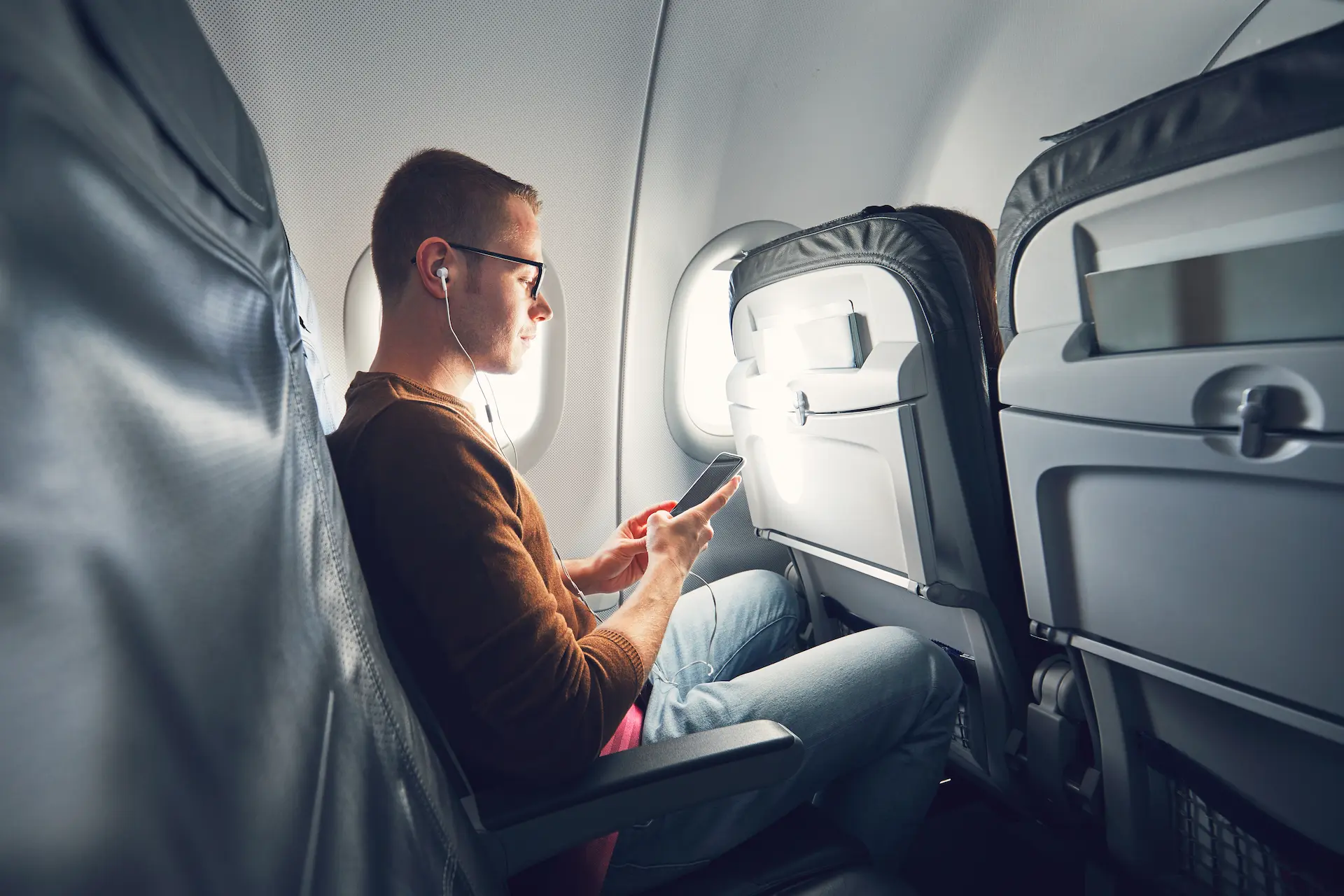 Man reading a travel blog on his phone while on a plane